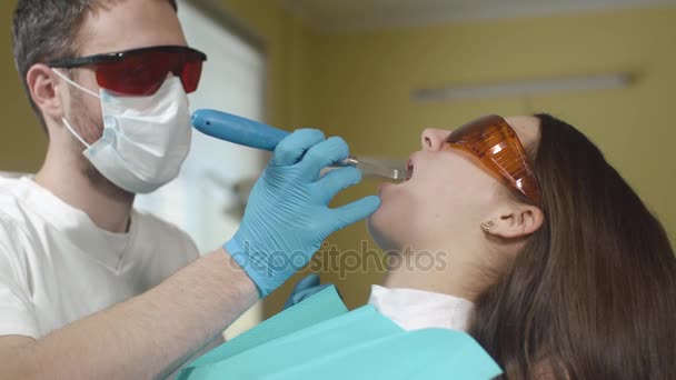 Paciente do sexo feminino recebendo tratamento com equipamento odontológico de luz UV. Odontologia . — Vídeo de Stock