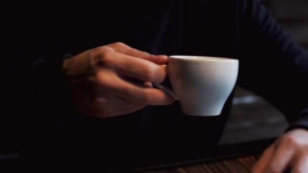 Silhuetten av ung man som dricker kaffe bredvid fönstret i caféet. — Stockvideo