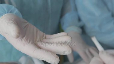 Ameliyat için hazırlık. Yardımcısı cerrah doktor neşteri verir. Cerrahın elleri içinde tıbbi neşter