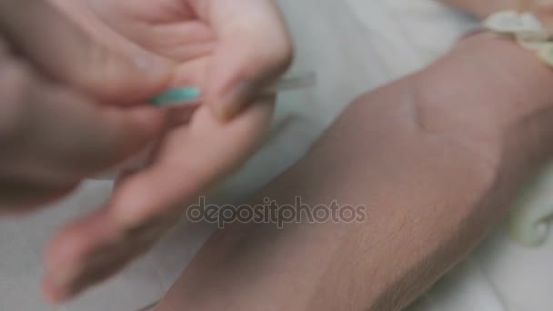 El primer plano de la mano masculina coloca una aguja debajo de la piel del paciente. La mano sin guantes. Concepto de infección o cirugía de la sangre . — Vídeo de stock