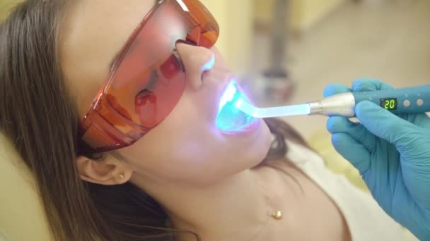 Paciente do sexo feminino recebendo tratamento com equipamento de luz UV dental . — Vídeo de Stock