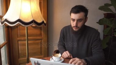 Lviv, Ukrayna - Ocak 2017: Cafe modern dizüstü bilgisayar üzerinde çalışan genç adam