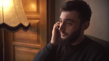 rahat kafede cep telefonuyla konuşan genç adam.