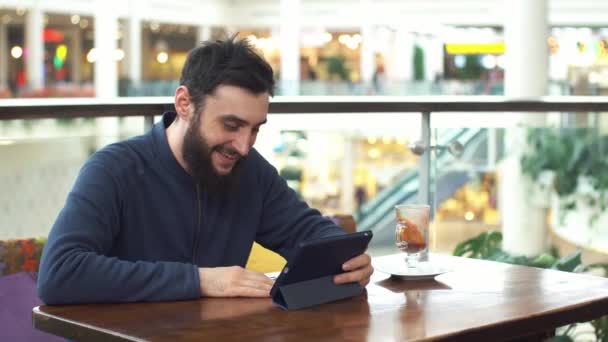Fiatal, boldog ember beszélget tabletta bevásárlóközpontban — Stock videók