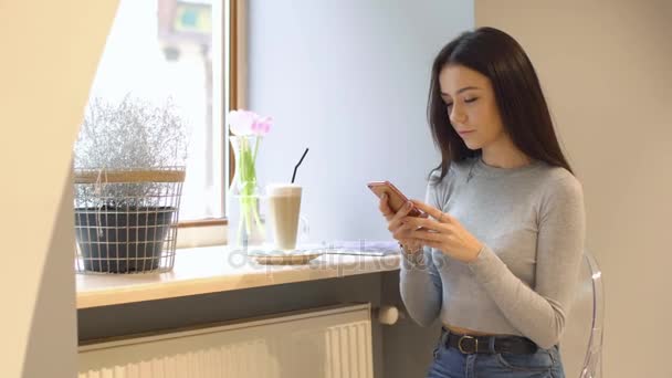 Krásná mladá dívka pomocí smartphone v kavárně — Stock video