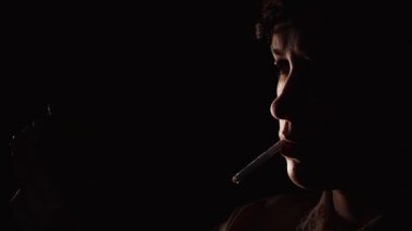 genç kadın bir eşleşme kullanarak bir sigara yakmak için çalışıyor. O ışık sigara siyah arka plan cant