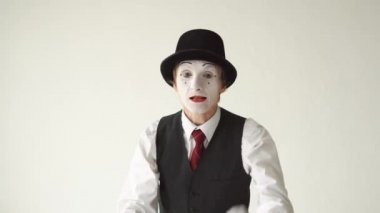 adam beyaz arka plan üzerinde MIME duran ve yemin ediyor, kameraya bakıyor