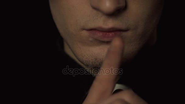 Um distúrbio mental, um padre de fundo negro. Põe o dedo nos lábios e diz Shhhh. Close-up — Vídeo de Stock