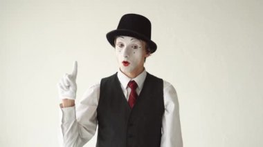 Beyaz arka plan üzerinde duran ve kameraya bakarak adam MIME. Parmak dalgalar 