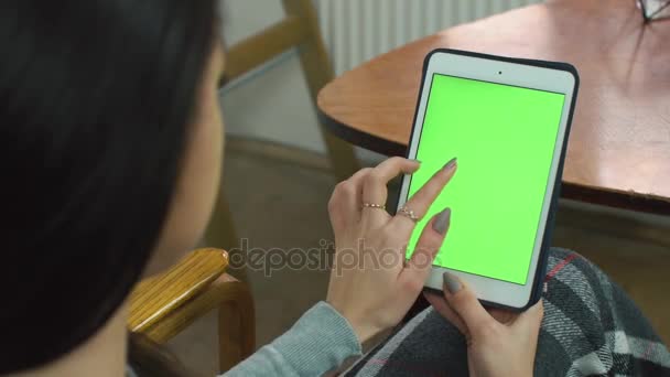 Девочка с планшетом с зеленым экраном, сидящая дома на удобном стуле — стоковое видео