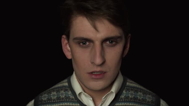 Portrait of a young man who looks into the camera and prays on a black background — Stock Video