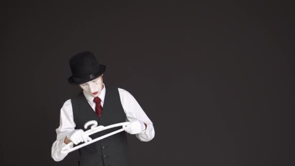 Man Mime speelt met een hanger van de kleding op een zwarte achtergrond — Stockvideo