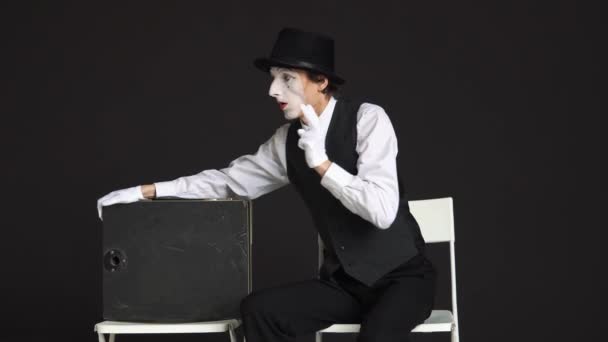 Homem MIME guardando a pasta com o dinheiro. O ator está sentado em uma cadeira no fundo preto — Vídeo de Stock