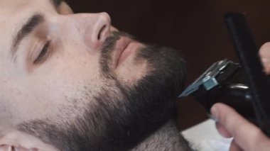 El kesme sakal kesme makinesi, berber berber. Closeup video, 4k. Kuaför elektrik makası ile çalışır