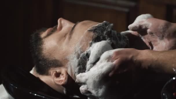 Kapper wassen hoofd van de man in barbershop — Stockvideo