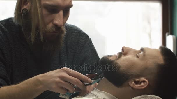 Barbero barba de corte a mano con clipper en la barbería. Peluquero trabaja con el trimmer eléctrico — Vídeo de stock