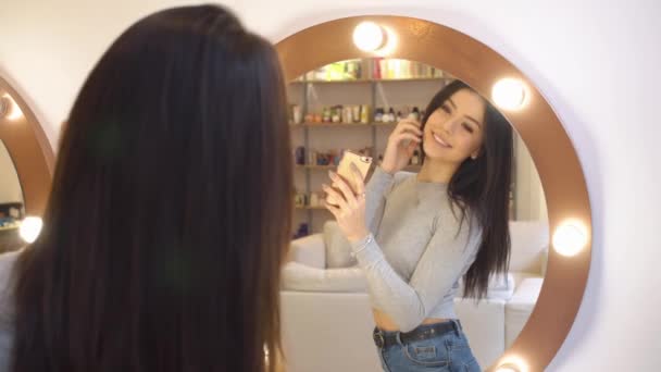 젊은 예쁜 여자는 거울 앞 자신의 사진을 걸립니다. 그녀의 눈에서 환상적인 반사와 미용실에 그녀 — 비디오