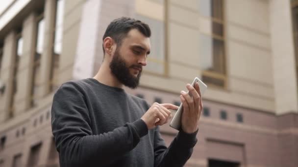 Щаслива борода молодий чоловік використовує планшетний комп'ютер на вулиці на заході сонця — стокове відео