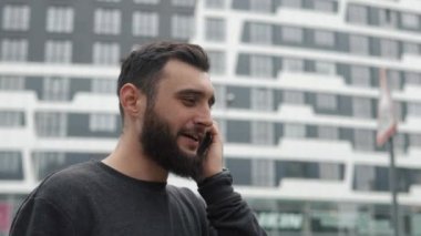 binalarıyla yakınındaki telefonda konuşurken sakallı genç adam