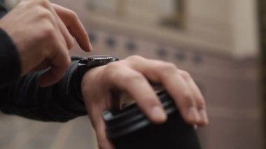 Bir fincan kahve ile onun akıllı izle ayakta sakallı adam denetler