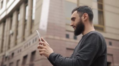 Tablet bilgisayar sokakta günbatımında kullanan mutlu sakal genç adam