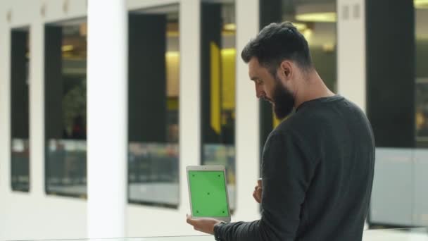 Человек показывает белую табличку с зеленым экраном в руках — стоковое видео