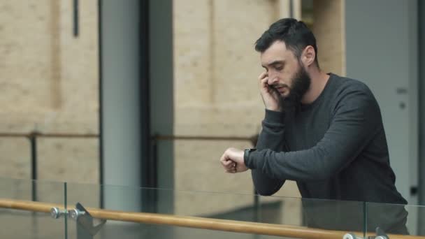 Besorgter Mann spricht auf seinem Smartphone im Flur — Stockvideo