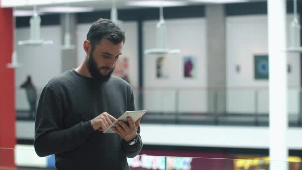 Muž si čte jeho postavení tabletu, na světlé chodbě — Stock video