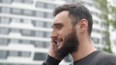 binalarıyla yakınındaki telefonda konuşurken sakallı genç adam