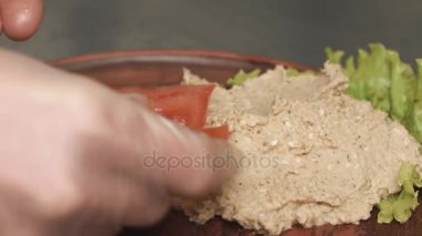 Adam domates salatası üzerinde ahşap tabak koyar