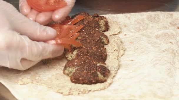 El hombre pone rodajas de tomate en la carne asada en una pita — Vídeos de Stock