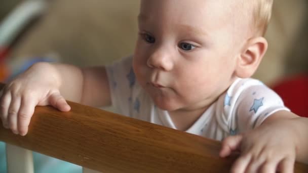 Niño pequeño se sienta en la cama de madera — Vídeo de stock