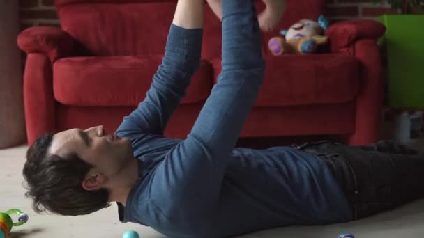 Padre juega con un niño pequeño en el suelo — Vídeos de Stock