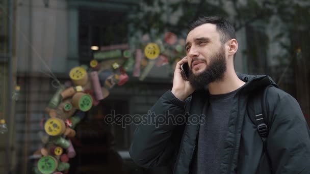 El hombre habla en el Smartphone de pie en algún lugar de la ciudad — Vídeo de stock