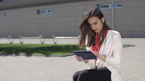 Женщина читает что-то на планшете стоя с красным чемоданом — стоковое видео