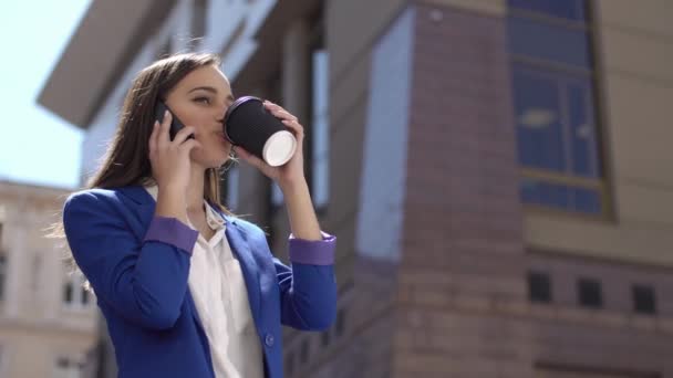 Женщина пьет кофе с айфоном в руке — стоковое видео