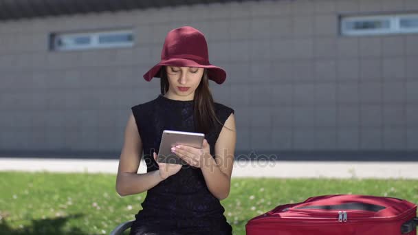 Mulher sorridente de chapéu vermelho lê algo em seu tablet — Vídeo de Stock