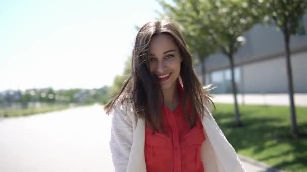 Mulher bonita na camisa vermelha caminha fora em um dia ensolarado — Vídeo de Stock