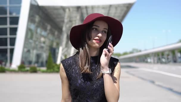 Женщина в красной шляпе разговаривает по телефону — стоковое видео