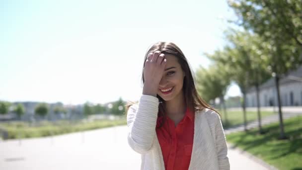 Красива жінка в червоній сорочці виходить на вулицю в сонячний день — стокове відео