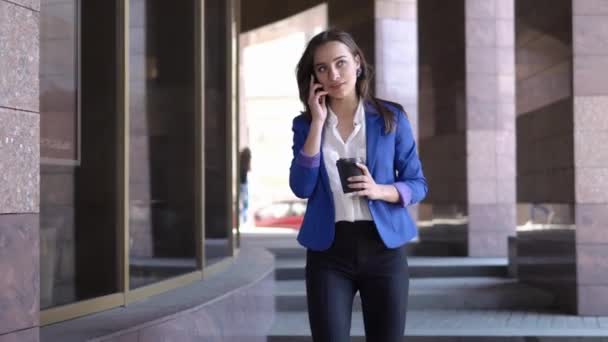 Mujer de negocios comprueba su teléfono de pie en la ciudad — Vídeos de Stock