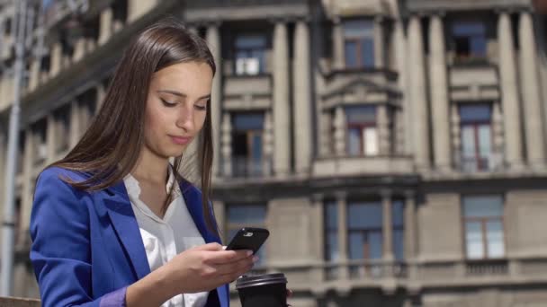 Деловая женщина проверяет телефон, стоящий в городе — стоковое видео