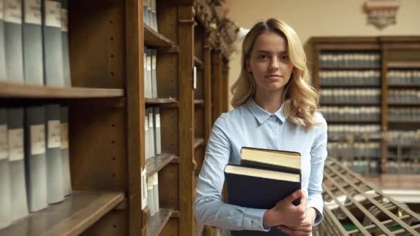 Estudiante camina con gran libro en la biblioteca — Vídeos de Stock