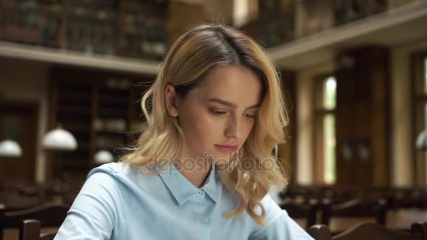 Estudiante trabaja con libros y laptop en la biblioteca — Vídeos de Stock