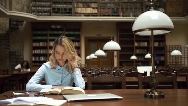 Studente lavora con libri e laptop in biblioteca — Video Stock