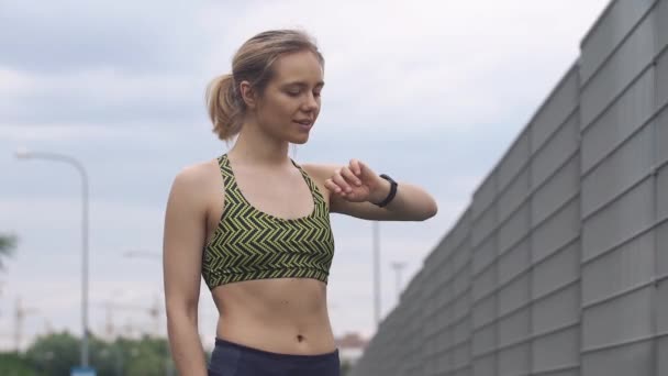 Біг жінка перевіряє свій фітнес-браслет — стокове відео