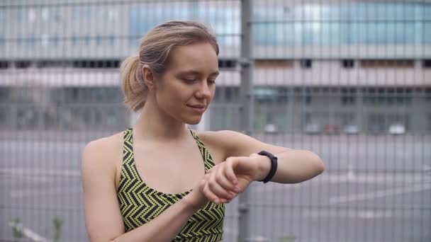 Correr mujer comprueba su pulsera de fitness — Vídeos de Stock