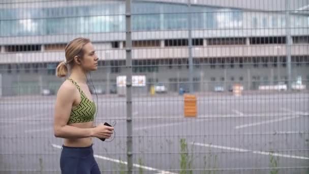 Correr mujer escucha la música en el camino — Vídeo de stock