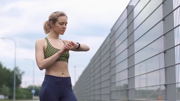 Біг жінка перевіряє свій пристрій, що носить — стокове відео