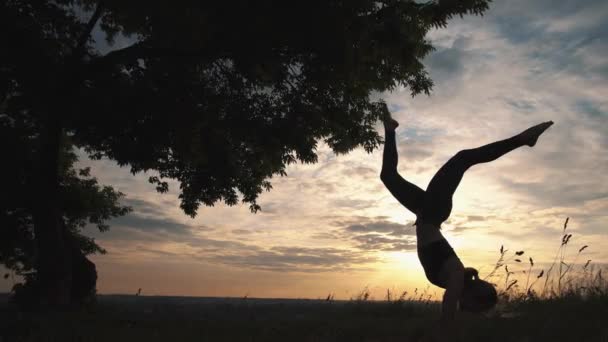 Silueta de una mujer practicando yoga al amanecer — Vídeos de Stock